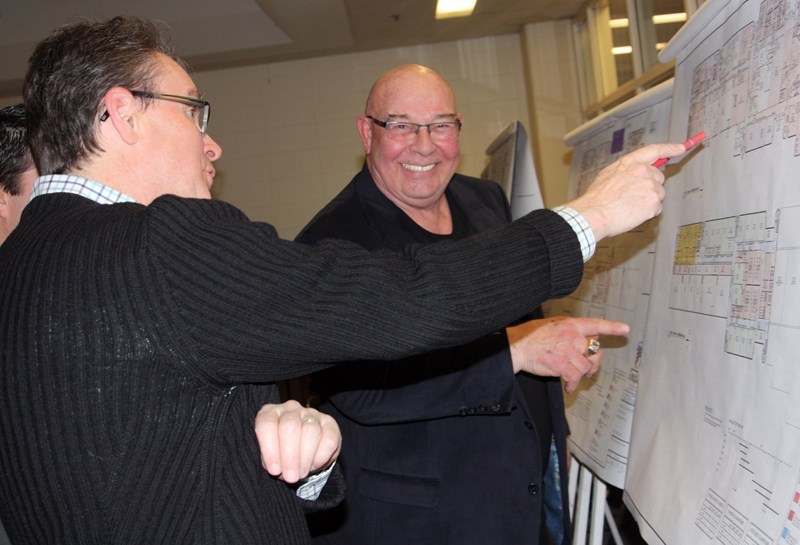 Smiling Okotoks Councillor Ray Watrin, a former teacher at Foothills Composite High School, studies drawings of a proposed $22-million modernization of the school during an