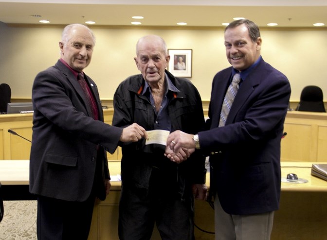 MD of Foothills Mayor Larry Spilak, right and Deputy Mayor Ted Mills, left, accept a donation of $50,000 from High River resident Oliver Perry at a regular meeting of council 