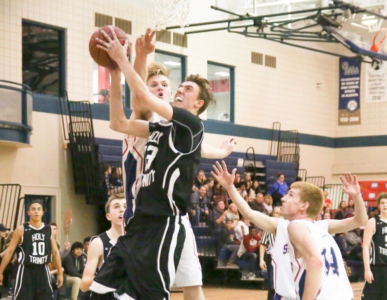 Holy Trinity Academy Knight Seth Moser goes in for a lay-up as Strathmore Spartan Jonathon Le May defends on March 2 in Strathmore.