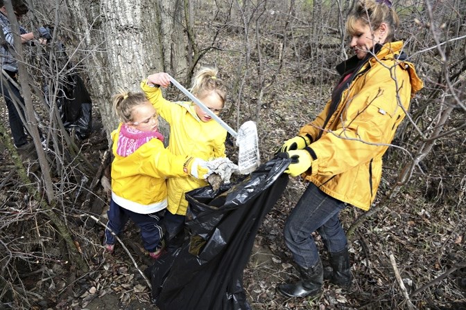 Rebecca Beach tosses garbage in to a trash bag with her two daughters Josslyn and Caitlin during the annual Sheep River Valley clean-up event in 2014.