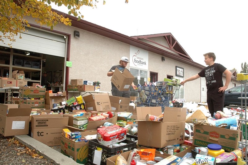 Jacob Helton, right, and Jordan Wygle help sort through a large pile of donations outside the Okotoks Food Bank collectied during a Sept. 17 community-wide food drive.