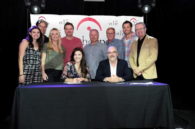 Okotoks singer/songwriter Maddison Krebs, front left, signs a contract with publishing company ole Majorly Indie founder and CEO Robert Ott, right, and other staff at the