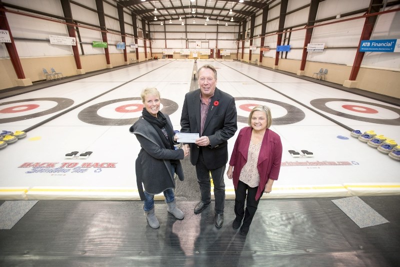 Oilfields Curling Club treasurer Kerrie Gallup, left, and Jane Libbus accept a cheque from Livingstone-MacLeod MLA Pat Stier for $13,595 from the Community Facility