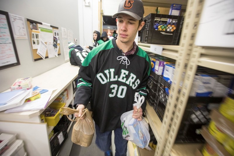Oilers Midget AA Black player Dylan Jensen carries donated groceries into the Okotoks Food Bank Association on Nov. 30.