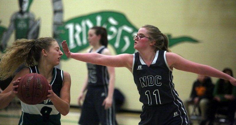 Holy Trinity Academy Knight Lauren Sinclair, left, is closely guarded by a Notre Dame Collegiate Timberwolf on Jan. 11 in Okotoks.