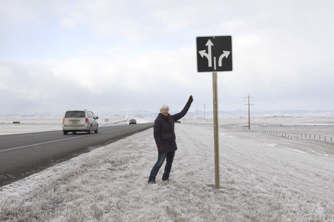 Cherie Andrews, owner of Chinook Honey Farm, stands near a sign indicating a right-turn lane only on Highway 7 at 16 Street (Big Rock Trail). The busy intersection has been