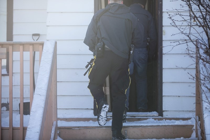 Okotoks RCMP officers walk up the stairs into an Okotoks home after arresting two in relation to an investigation of alleged theft of construction equipment.