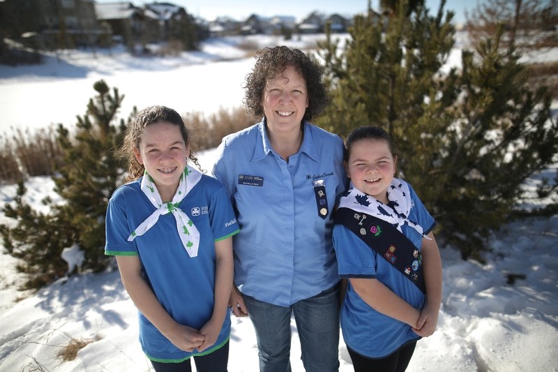 Pathfinder McKenzie Reid, left, and guide Hannah Reid, right, with their mother Michelle, a Guider, on Feb. 11.