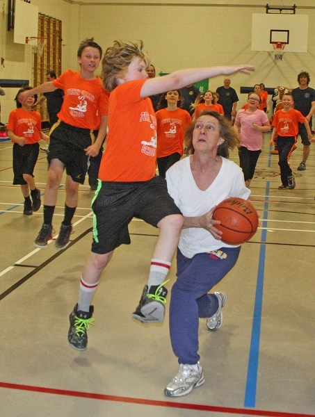 Cody Gentry tries to block Turner Valley RCMP employee Lynne Williams&#8217; shot during a friendly basketball game at Turner Valley School on April 12. The game raised money 