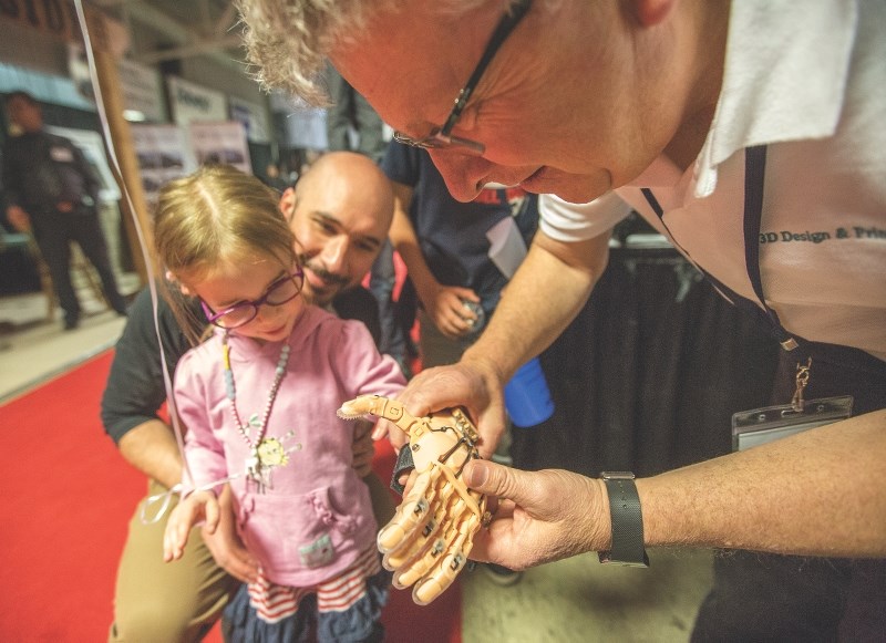 Bob White of CountryG 3D fits a 3d printed prosthetic hand for Madeline Kruszynski and her dad Carl at the 2016 trade show. This year&#8217;s Business Expo takes place April