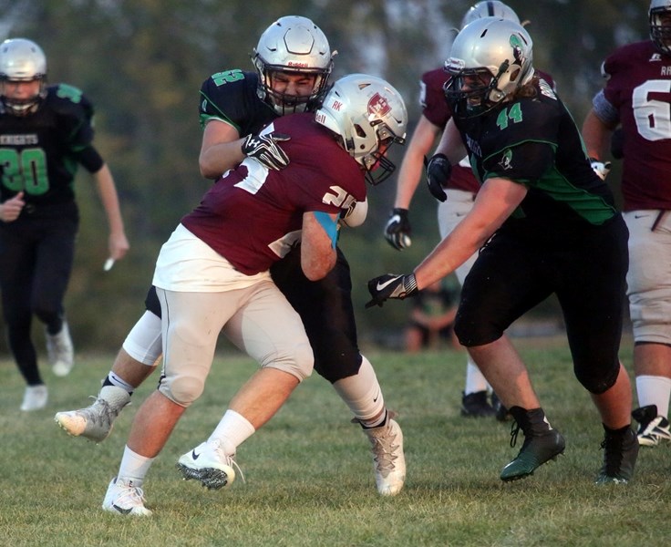 Holy Trinity Academy Knight Jacob Kamajian (52) wraps up Holy Rosary Raider runningback Dylan Gottinger while Knights Evan Bruynzeel comes into assist on the tackle Sept. 1