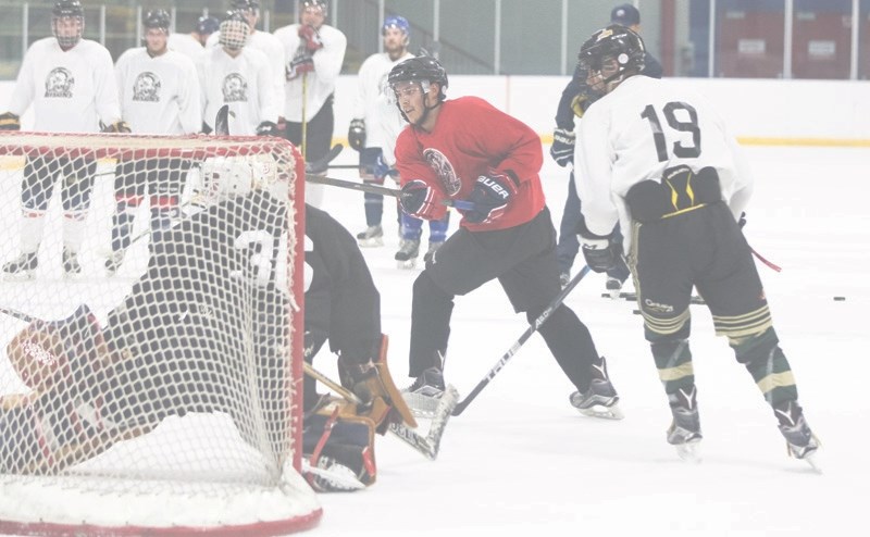 Brennan Fuoco, red jersey, attempts to fire a shot by defender Braeden Germain and goalie Matthew McDonald at the Okotoks Bisons training camp on Aug. 30 at the Murray Arena.