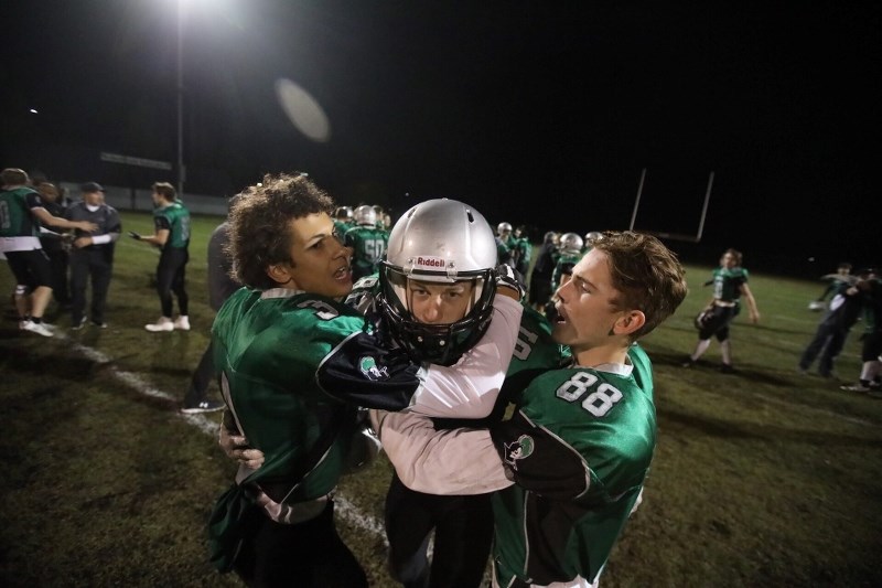 Holy Trinity Academy Knights defensive back Nick Dielissen, centre, is mobbed by teammates Joash Binet and Riley Dallaire after knocking down a pass on the final play of the