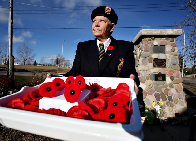 Linda Macaulay holds a box of poppies at the Turner Valley cenotaph. The annual poppy drive kicks off Oct. 27.