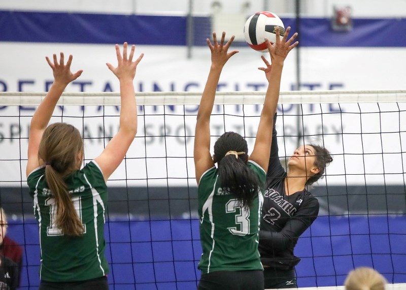 Foothills Falcon Jazmyn Kellogg tips over Strathcona-Tweedsmuir Spartans Megan Norris (11) and Emy Udoh Nov. 8 in the Foothills Athletic Council Senior girls volleyball final 