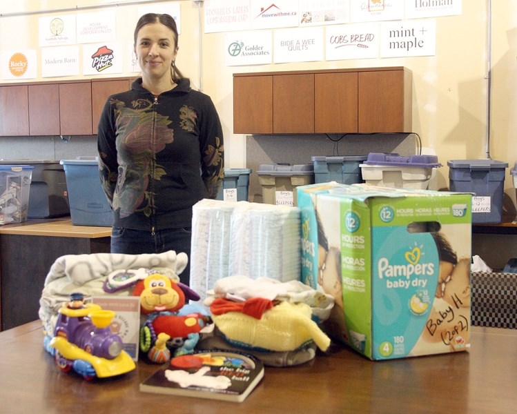 Rachel Swendseid, president and co-founder of It Takes a Village, shows off the contents of a baby box the group provides to parents of children age 0 to 12 months facing