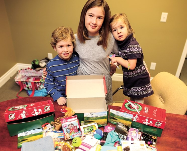 Lana Thiessen&#8217;s children, Levi, Amelia, and Ella, pack shoeboxes with items for a child in need through Operation Christmas Child.