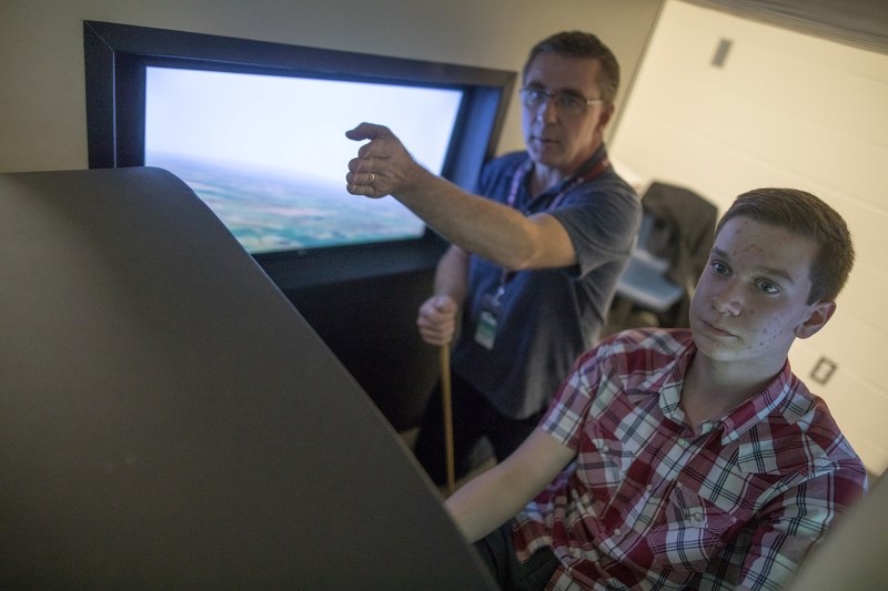 Wes Harder, of Jazz Aviation, gives instructions to Grade 12 student Travis Burnell on a flight simulator at Foothills Composite High School on Nov. 24.