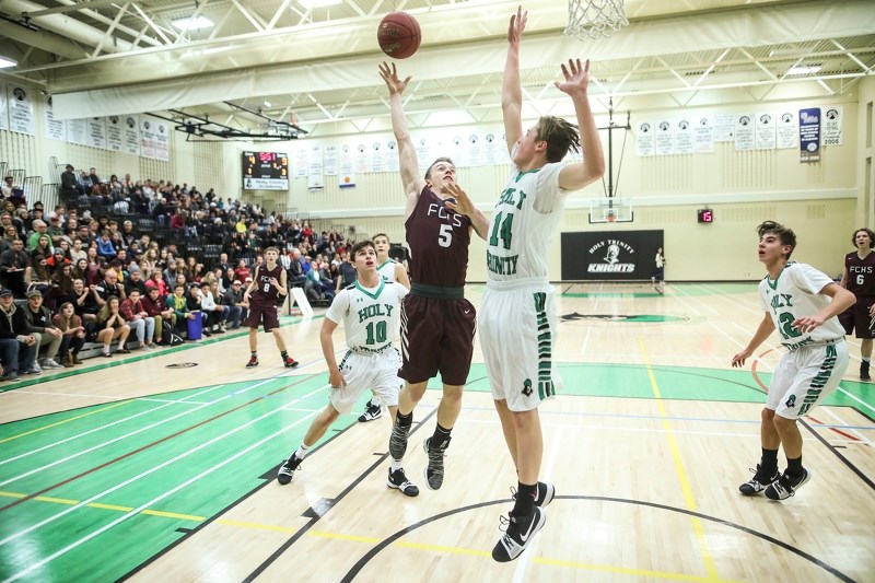Foothills Falcon Tyler Pitcher shoots over Holy Trinity Academy Knight Carson McKenzie on Dec. 21. The Falcons won the rivalry game 88-64 in a packed HTA gym.