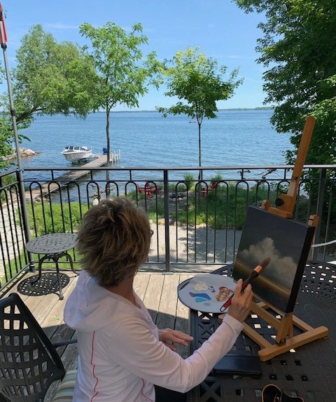 Melody Lynn Madden is shown working on a painting on her back deck - a place that regularly inspires her. An exhibition of her work will be unveiled at the Orillia Museum of Art & History later this month.