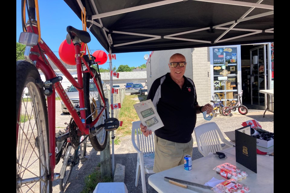 Barry Middleton poses with the money from his first bike sale, beside one of the first bikes he sold at The Bike Stop of Orillia. He officially retired today, handing over the reins of the store to Thomas Hulton and Paul Belanger. Sam Gillett/OrilliaMatters