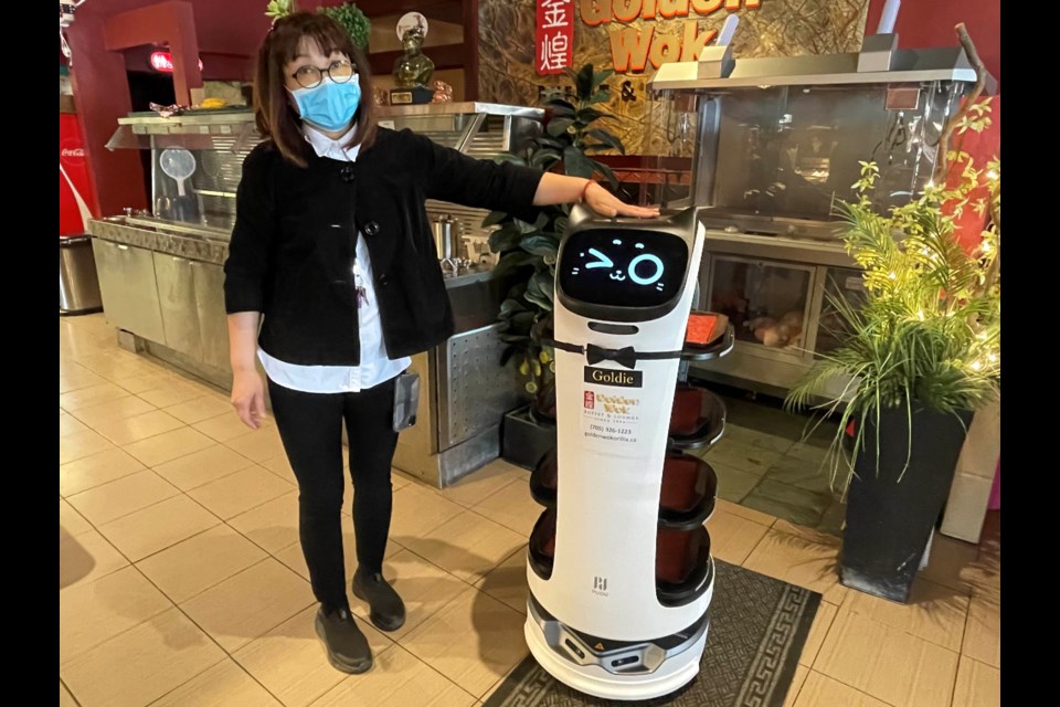 Golden Wok Buffet and Lounge owner Katty Po stands with her newest staff member, "Goldie" the robot.