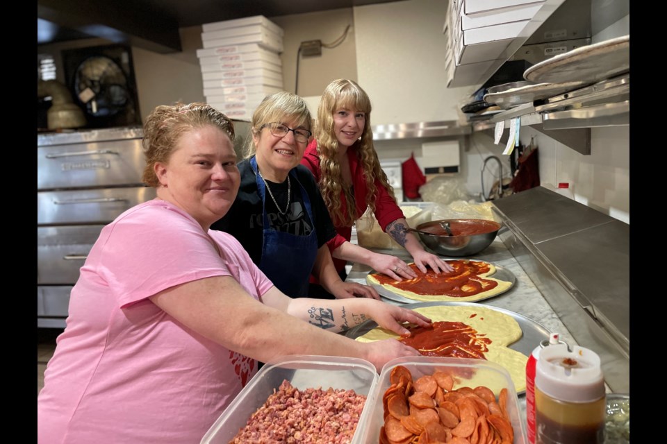 Alissia Martin, front, and Jessica Bower, back, made heart-shaped pizzas with Tops in Pizza co-owner Toni Marinakos, middle, ahead of Valentine's Day, just as they once did in kindergarten. 