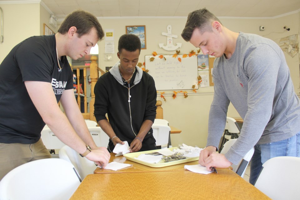William Murphy, left, Elijah Emefe, centre, and Darren Trafford, police foundations students at Georgian College in Orillia, set the table Tuesday at the Lighthouse Soup Kitchen and Shelter. Nathan Taylor/OrilliaMatters