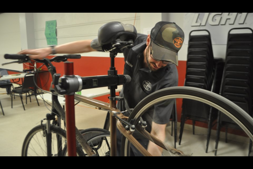 Jacob McClelland, co-owner of the Crank & Sprocket Bicycle Co., works on a bike during Saturday’s repair event. Andrew Philips/Orillia Matters