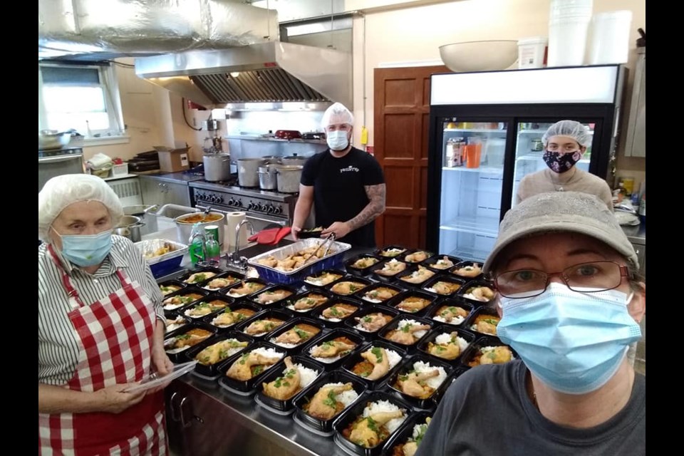 Volunteers from The Sharing Place Food Centre are shown preparing meals in the St. James' Anglican Church kitchen.