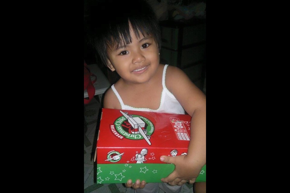 A young recipient of an Operation Christmas Child shoebox is shown.