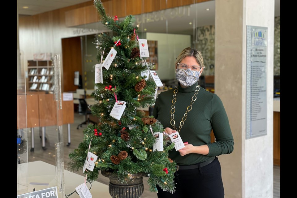 Amy Lambertsen, head of the circulation department at the Orillia Public Library, is pictured putting tags on the tree for the Santa for Seniors program.  