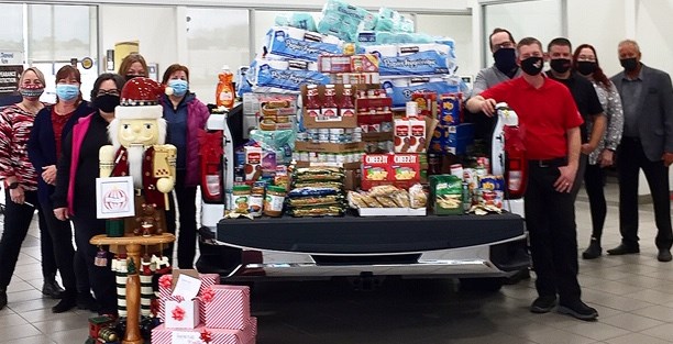 Staff from Jim WIlson Chevrolet Buick GMC stand with a truck crammed with donations to The Sharing Place Food Centre.