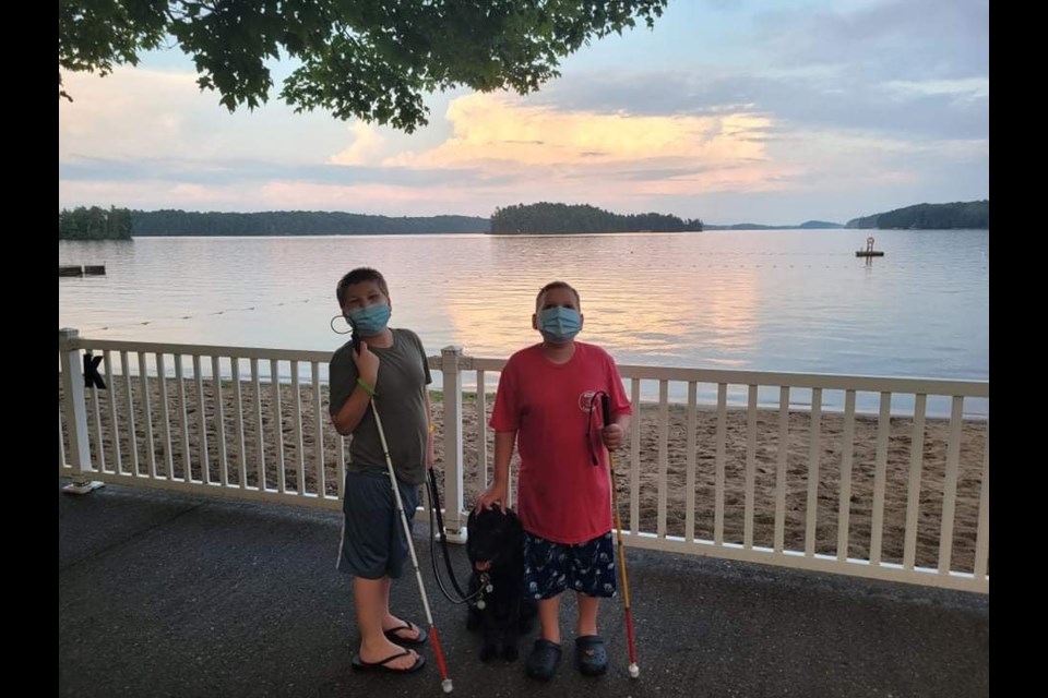 Mason (left) and Ollie (right) with Hope in the middle, and the sun setting on Lake Joe in the background. Supplied photo