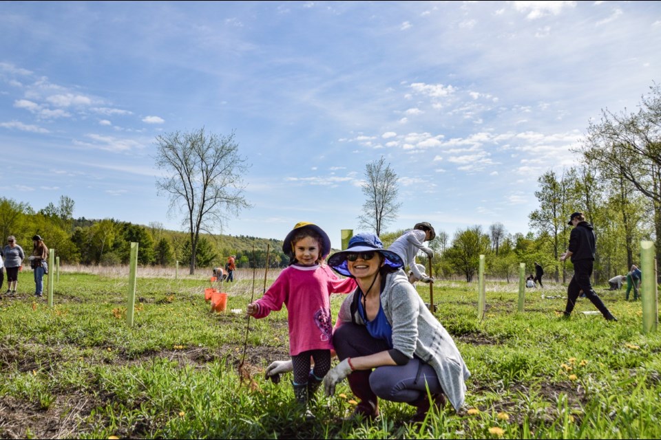 A mother and daughter volunteered to plant trees to cool the Pine River.