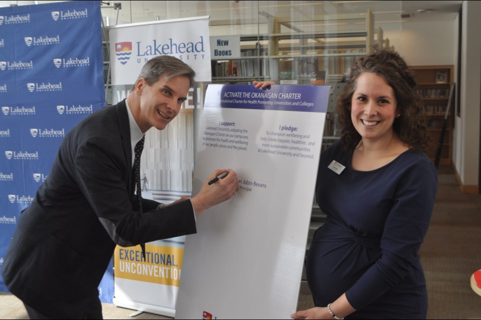 Lakehead Orillia principal Dean Jobin-Bevans is pictured Wednesday with Elana Weber, the school’s athletics and wellness co-ordinator, as he signs the Okanagan Charter: An International Charter for Health Promoting Universities and Colleges. Andrew Philips/OrilliaMatters