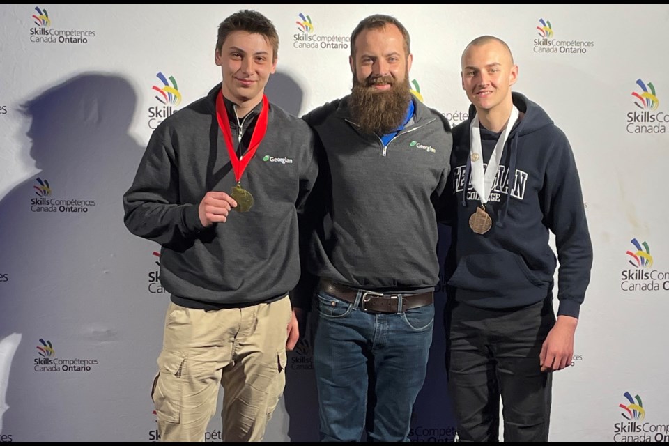 Ethan McCallum, left, and Ryle Reynolds, right, mechanical technician—precision skills students at Georgian College, are shown with instructor Brett Austin at the Skills Ontario Competition.