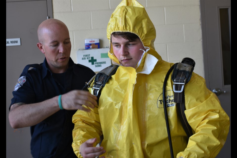 Patrick Fogarty student Anton Van Yzendoorn gets some help from a firefighter as he straps on tanks over his HAZMAT suit as part of an Emergency Preparedness Week exercise. Dave Dawson/OrilliaMatters