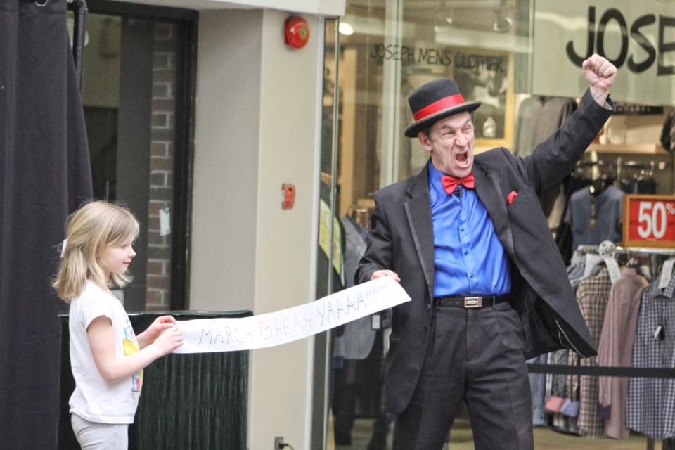 An audience member helps magician Steve Baker unfurl a "March break" banner during Baker's show Monday at the Orillia Square mall. Nathan Taylor/OrilliaMatters