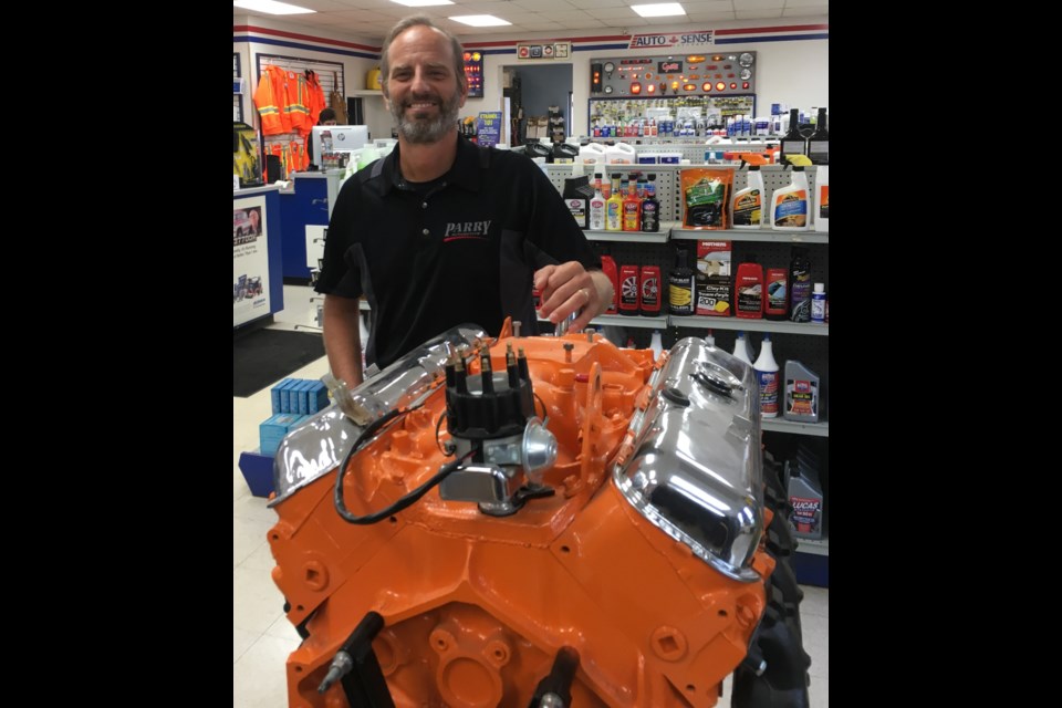 Steve Van Kessel, owner of Parry Automotive, is shown inside the automotive parts store with a restored motor. Contributed photo