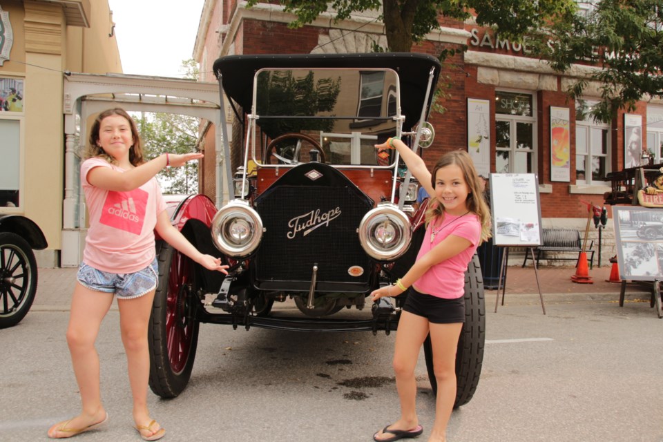 Laiken Sloane, 10, and her sister, Brynn, pose with their family car, a 1912 Tudhope 4-36 Touring, during Saturday's Downtown Orillia Classic Car Show. The two are great-great-granddaughters of J.B. Tudhope. Mehreen Shahid/OrilliaMatters