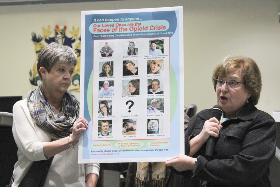 Esther Malmstrom, left, and Evelyn Pollock, whose daughter and son, respectively, died of opioid overdoses, are shown Tuesday during the Opioids and Other Drugs in Our Community forum at the Orillia City Centre. They are holding a poster bearing the images of loved ones lost to overdose. Nathan Taylor/OrilliaMatters