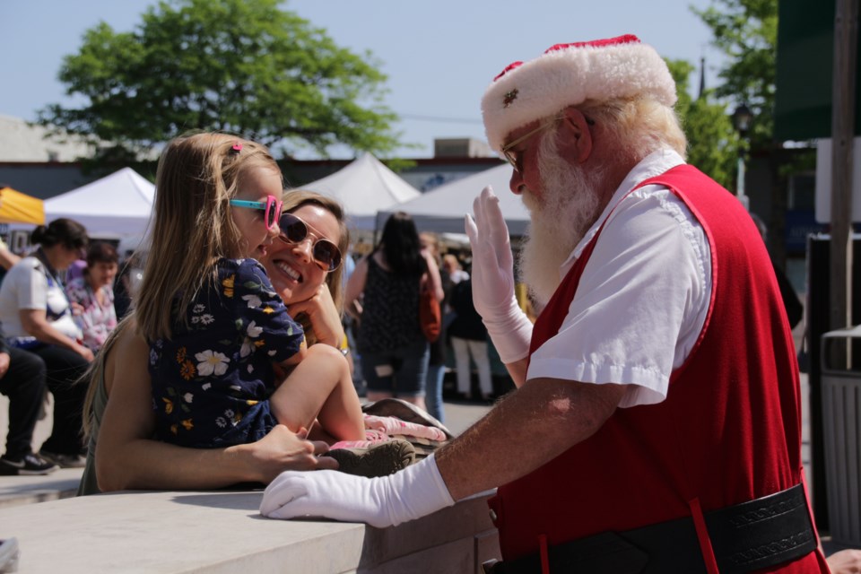 Santa Claus, visiting from Santa’s Village in Muskoka, gives a young market goer a high five Saturday as part of the annual Christmas in June celebration in Orillia. Mehreen Shahid/OrilliaMatters