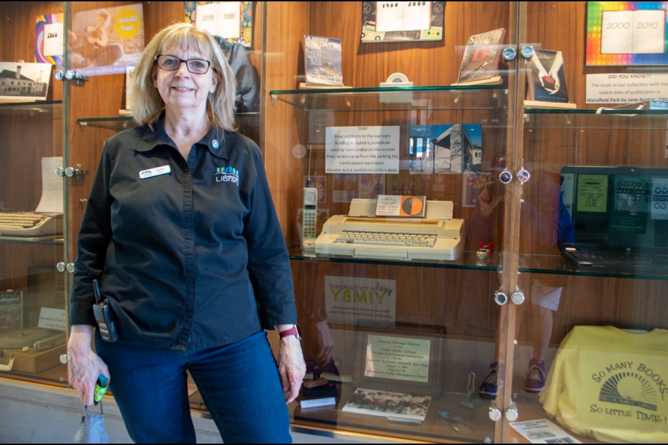 Jayne Turvey stands in front of a history exhibit that outlines the Orillia Public Library's story.