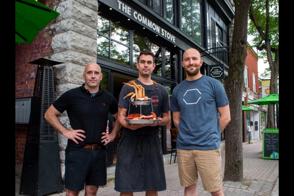 The Common Stove owners Darcy MacDonell, Ben Kersley, and Simon MacRae pose with their signature seafood tower. 