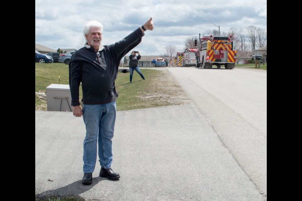 First-class Rama Firefighter Barry Denne waves to emergency service members who drove by his house to salute the end of his 44-year career on Saturday. Tyler Evans/OrilliaMatters