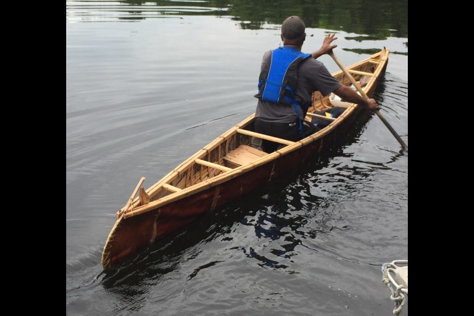 John Harrison paddles a canoe he built.