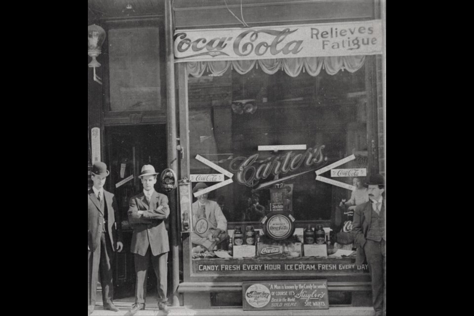 Men stand outside Carters in downtown Orillia where, as the sign indicates, free candy was made every hour and fresh ice cream was made every day.