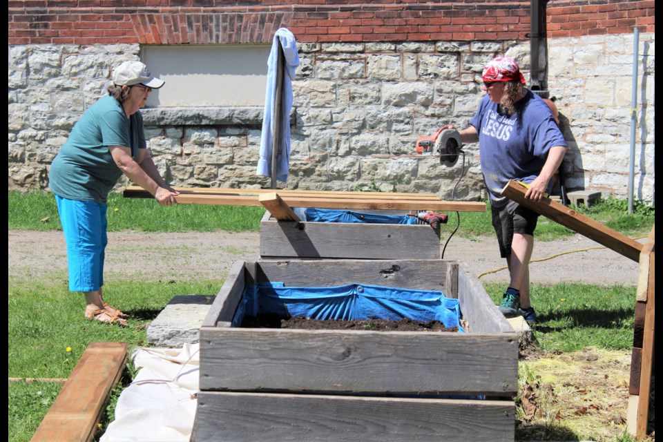 Christine Hager, left, chair of communications ministry at St. James' Anglican Church, and Jen Hill, the church's sexton, work on a new community garden box Tuesday. Nathan Taylor/OrilliaMatters