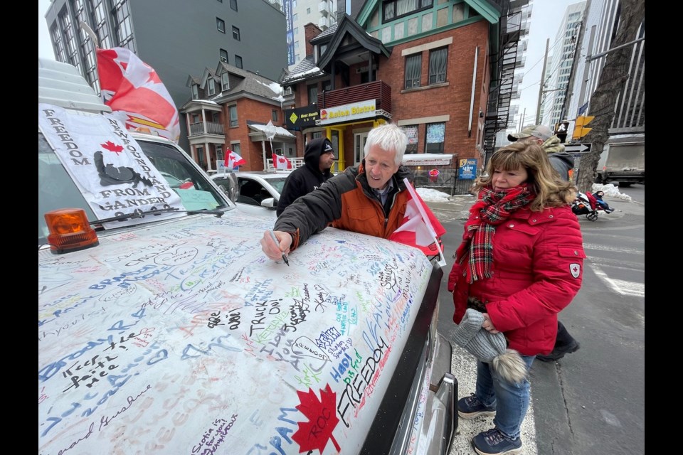 Peter and Ruth Leliveld sign a 'New Found Land' truck during the the protest in Ottawa on Friday. 